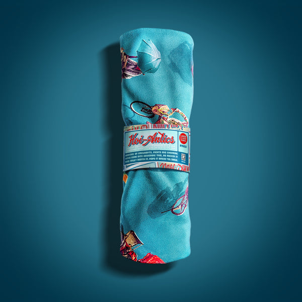 Front view of a rolled up large blue beach towel with a pattern of people on bicycles and motorcycles, featuring Hoi-Antics brand wrapper.