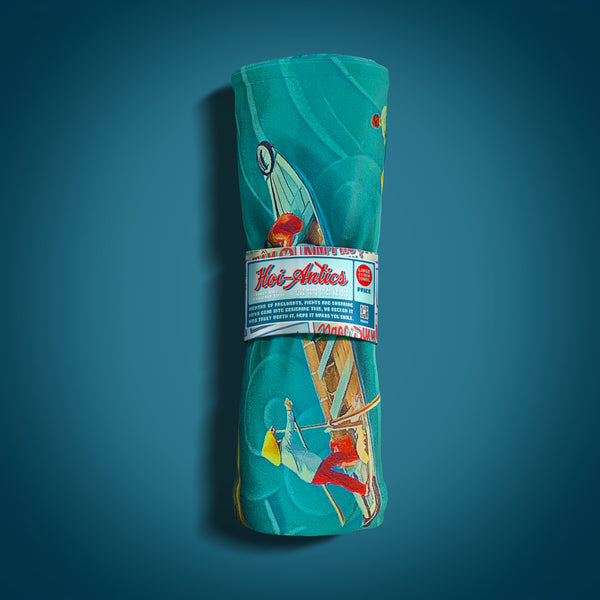 Front view of a rolled up large Mekong beach towel with a pattern of boats and people floating on asian inspired waves, featuring Hoi-Antics brand logo.