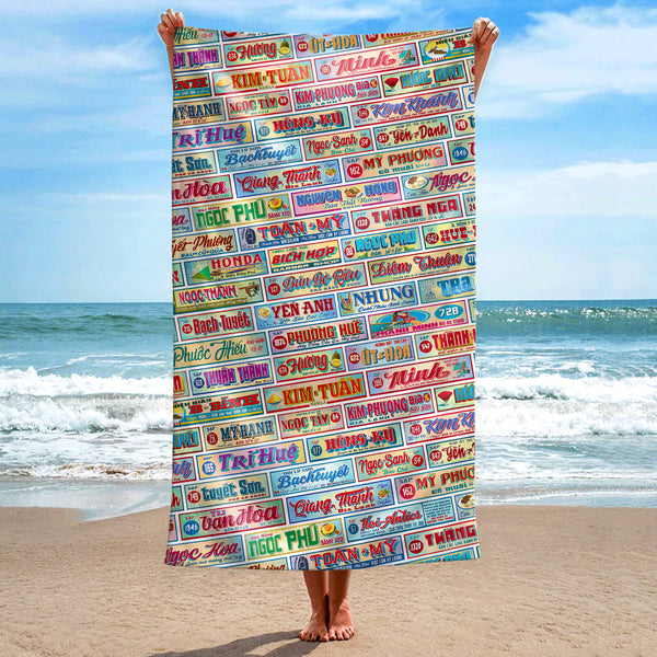 Front view of a large Shop Signs beach towel, held up at the beach, with a Vietnamese Shop Signage pattern, featuring Hoi-Antics brand logo.