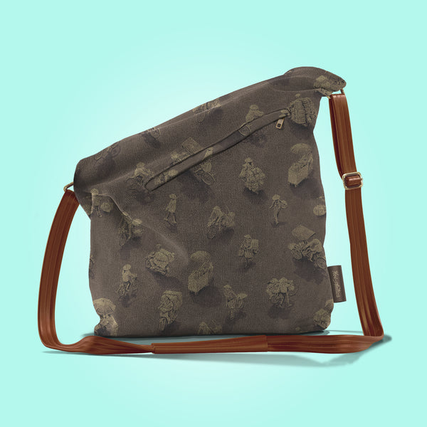 Back view of a closed antique umber canvas and brown leather bag with a pattern of people on bicycles and motorcycles, featuring Hoi-Antics brand logo.