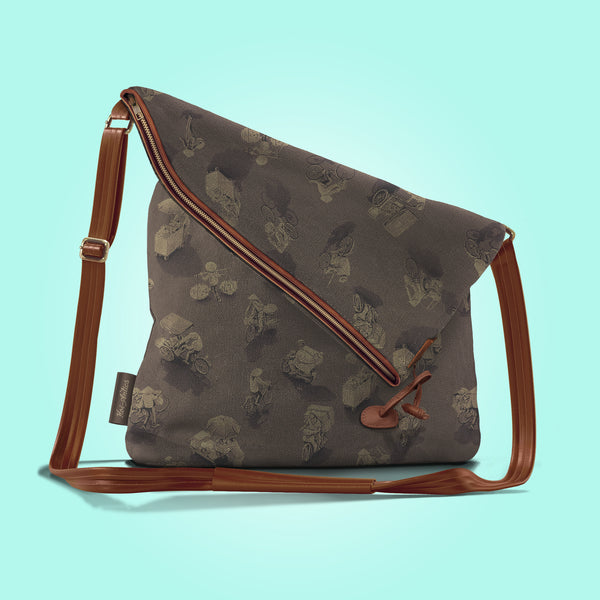 Front view of a closed antique umber canvas and brown leather bag with a pattern of people on bicycles and motorcycles, featuring Hoi-Antics brand logo.