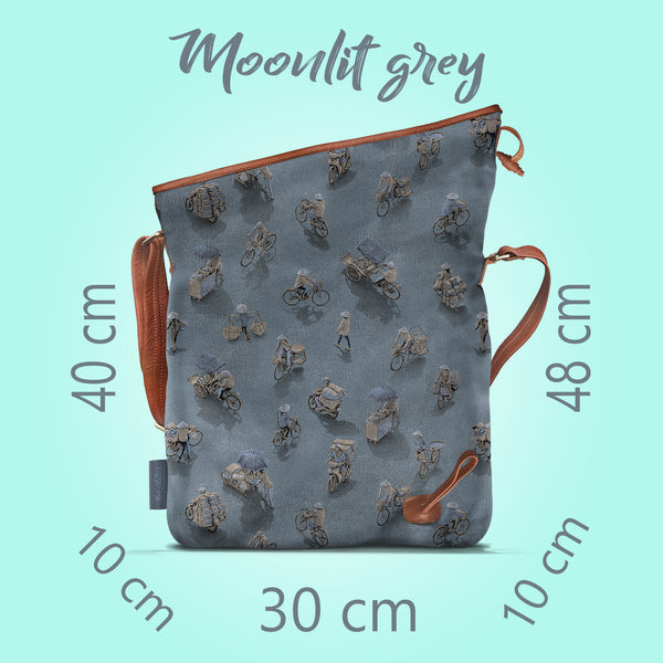 Front on view of a opened moonlit grey canvas and brown leather bag, with a pattern of people on bicycles and motorcycles, featuring Hoi-Antics brand logo. With text dimensions and color title.