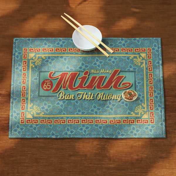 A distinct Vietnamese table mat, printed on canvas fabric, featuring a Vietnamese shop sign artwork, border and pattern.