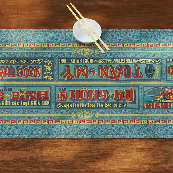 A distinct Vietnamese table runner, printed on canvas fabric, featuring Vietnamese shop sign artwork, borders and patterns.